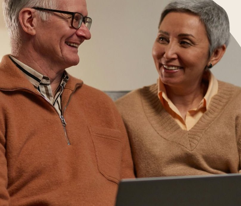 A couple laughing together while reviewing plans on a laptop