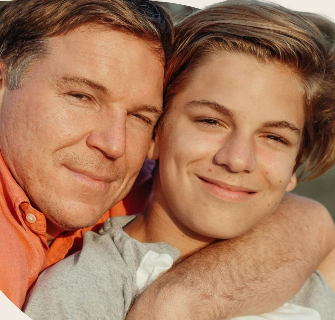 A father and teenage son smiling, cheek to cheek